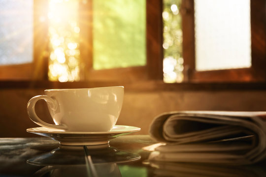 Coffee cup with news paper at coffee shop, summer vintage with sunlight background.