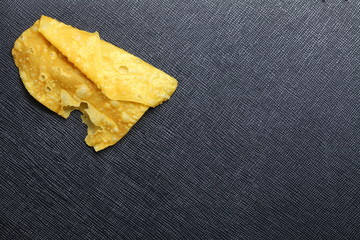 Crispy fried wonton sheet put on the black color leather surface background represent Thai and Chinese traditional cuisine.