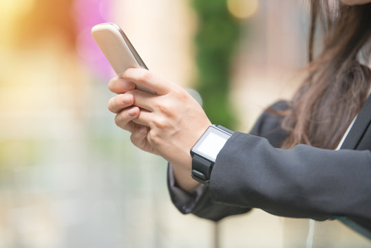 business woman holding smart phone and smartwatch