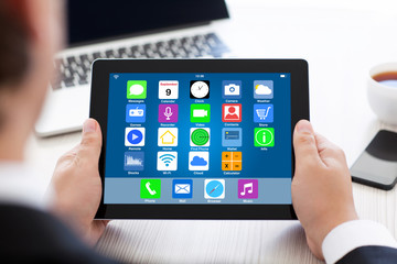 man holding tablet with home screen icons apps over table