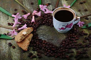 Rustic wooden background with cup of coffee and decorations. Heart shaped chalkboard. Spring flowers Top view