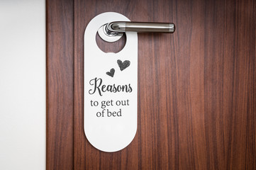 Door of hotel room with sign to get out of bed