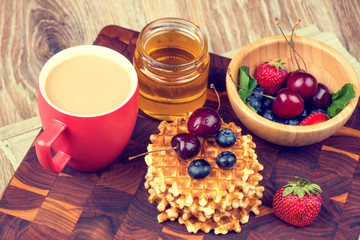Waffles with berries on wooden background. Toned image