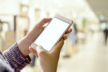 Woman using smartphone at airport corridor. Blank screen of smartphone for graphic display montage.