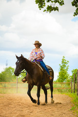 Cowgirl doing horse riding on countryside meadow