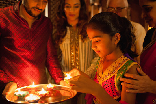 Family decorating with oil lamps on diwali.
