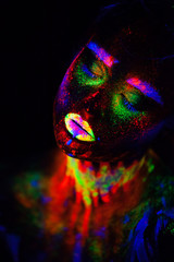 Beautiful extraterrestrial model woman in neon light. It is portrait of beautiful model with fluorescent make-up, Art design of female posing in UV with colorful make up. Isolated on black background