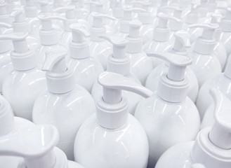 White unlabeled liquid soap bottles in supermarket, repeating pattern