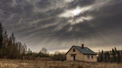 Landscape with house at day under cloudy sky. Spooky landscape with house in cloudy dull day.
