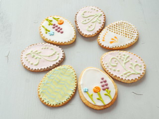 Easter egg shaped gingerbread glazed with royal icing. Homemade gift cookie upon wooden table. Easter treat. Food background. Selective focus on the front.