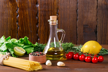 Spaghetti, tomatoes cherry, olive oil, herb and spices on old brown wooden background