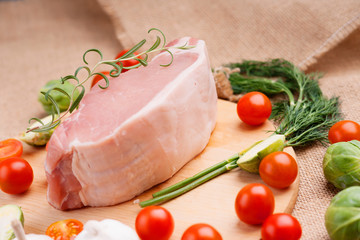 Raw pork on cutting board and vegetables 