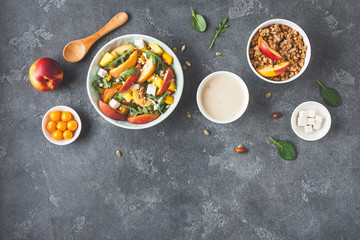 Breakfast with muesli, peach salad, fresh fruit, yogurt on dark background. Healthy food concept. Flat lay, top view