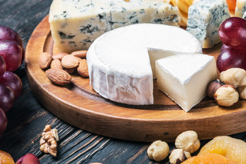 variety of cheeses with grapes and dried fruits on the table