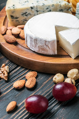 Assorted cheeses with grapes and nuts on a wooden table