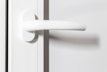 White plastic handle of a white door close-up.