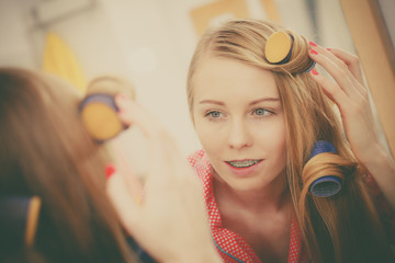 Naklejka premium Woman curling her hair using rollers