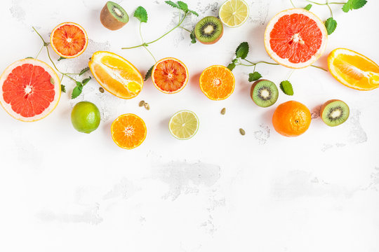 Fototapeta Fruit background. Colorful fresh fruit on white table. Orange, tangerine, lime, kiwi, grapefruit. Flat lay, top view, copy space