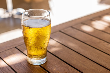 Glass of light beer on the wooden table.