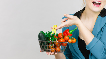 Woman holds shopping basket with vegetables