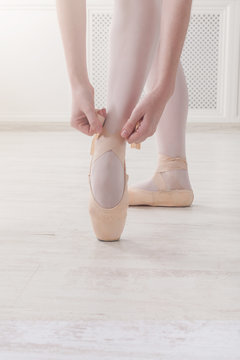 Closeup legs of ballerina puts on pointe ballet shoes
