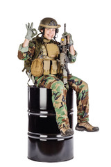 American soldier sitting on a black barrel . Isolated on a white background