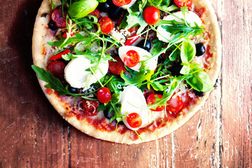Hot pizza with meat, basil and mozarella cheese on a dark background, top view. Pizza on the rustic wooden  table with copy space.