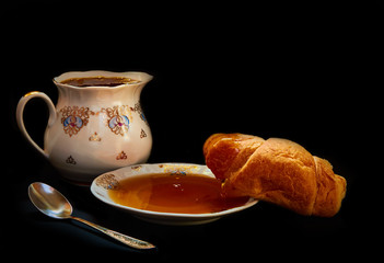 Croissant with honey and white plate on a black background