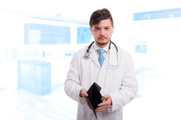 Portrait of disspointed male doctor holding his empty wallet