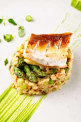 Fine dining, fish fillet breaded in herbs and spice on asparagus risotto.