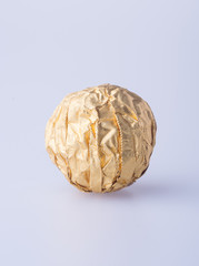 Chocolate ball in a gold foil paper on a background.