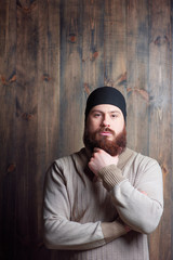 Confidence and manhood. Handsome young bearded man looking at camera on the wooden background
