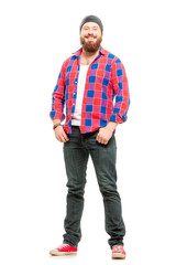 Fototapeta premium Really happy! Handsome young bearded man holding hands in pockets and looking at camera while standing against white background