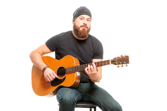 Man playing guitar. Bearded young men sitting and playing acoustic guitar over white