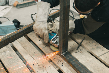 Man doing electroshooting of parts on the steel structure in the factory