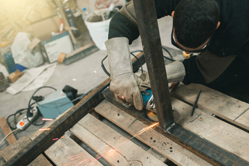 Man doing electroshooting of parts on the steel structure in the factory