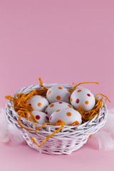 Easter eggs in the nest and basket on pink background