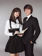 Happy teenagers in school uniform portrait. Handsome boy and beautiful brunette girl posing isolated on studio background.