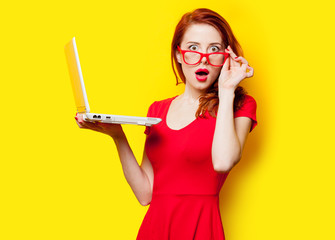 photo of beautiful young woman holding laptop on the wonderful yellow studio background - 143890081