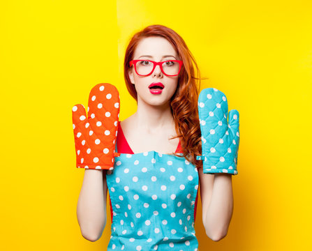 photo of beautiful young woman with potholders on the wonderful yellow studio background