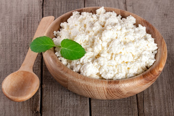 Cottage cheese in a wooden bowl on old wooden background