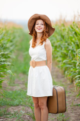 photo of beautiful young woman with suitcase on the wonderful field background