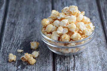 Popcorn in clear bowl on grey wooden plank table