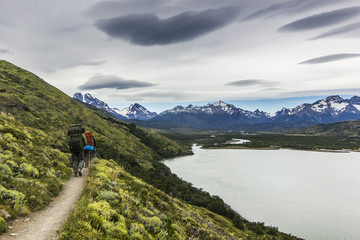Fototapeta na wymiar two men hiking in patagonia mountains, torres del paine with grey sky