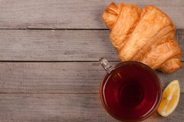 croissant with a cup of tea On an old wooden background. Top view