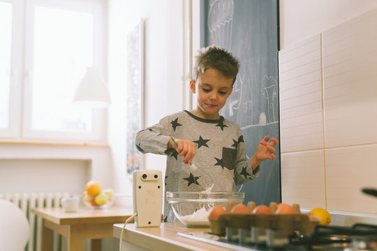Boy baking pancakes in kitchen