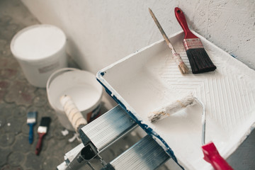 Wall prepared for painting. Brushes, buckets of paint, stairs near the wall