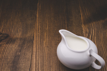 porcelain jug for milk on a wooden background/creamer on a wooden background