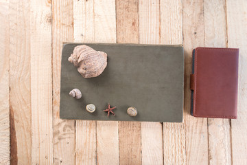 Notebook on a wooden background with seashells.