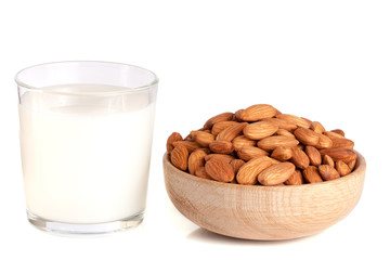 Almond milk in a glass and almonds in a wooden bowl isolated on a white background